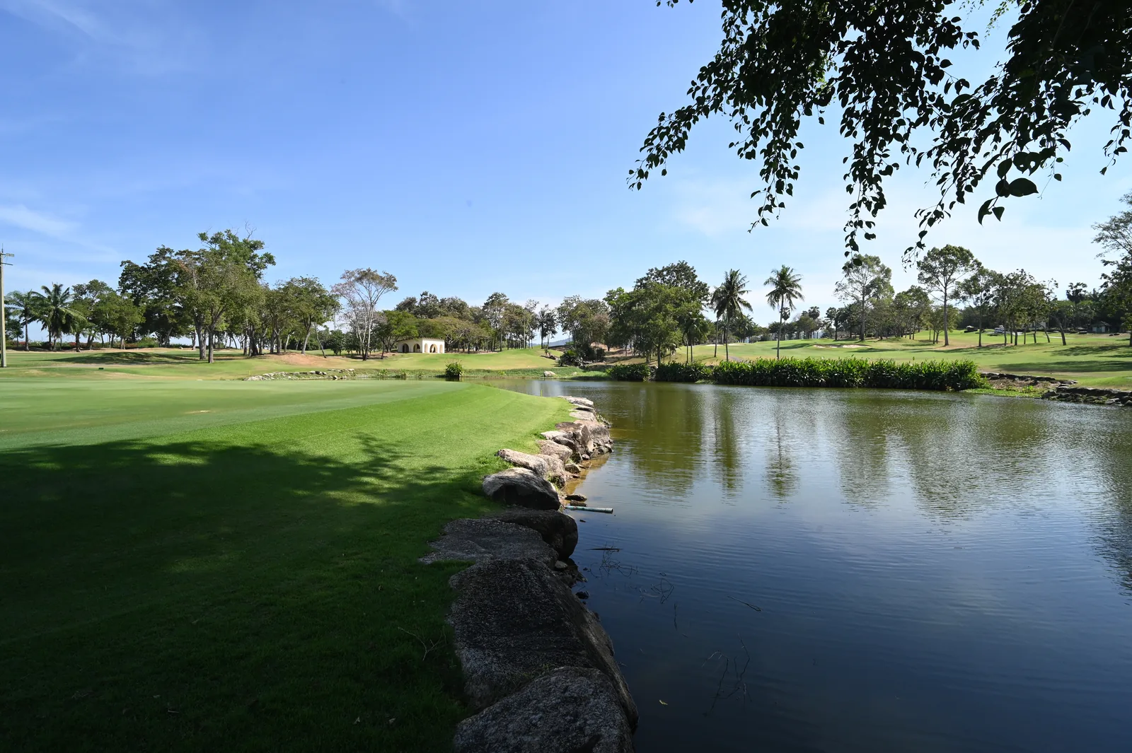 A green and stone-edged water hazard in Ban Chang, Rayong, photographed in December 2025.