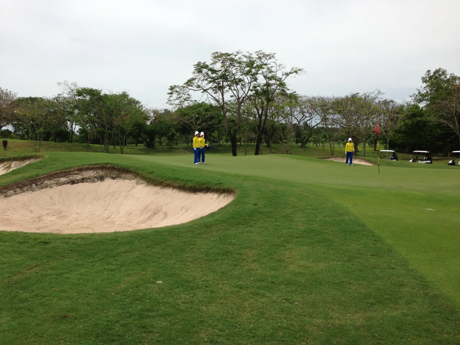 A bunker and green with caddies and golf carts at Siam Country Club Old Course in May 2013.
